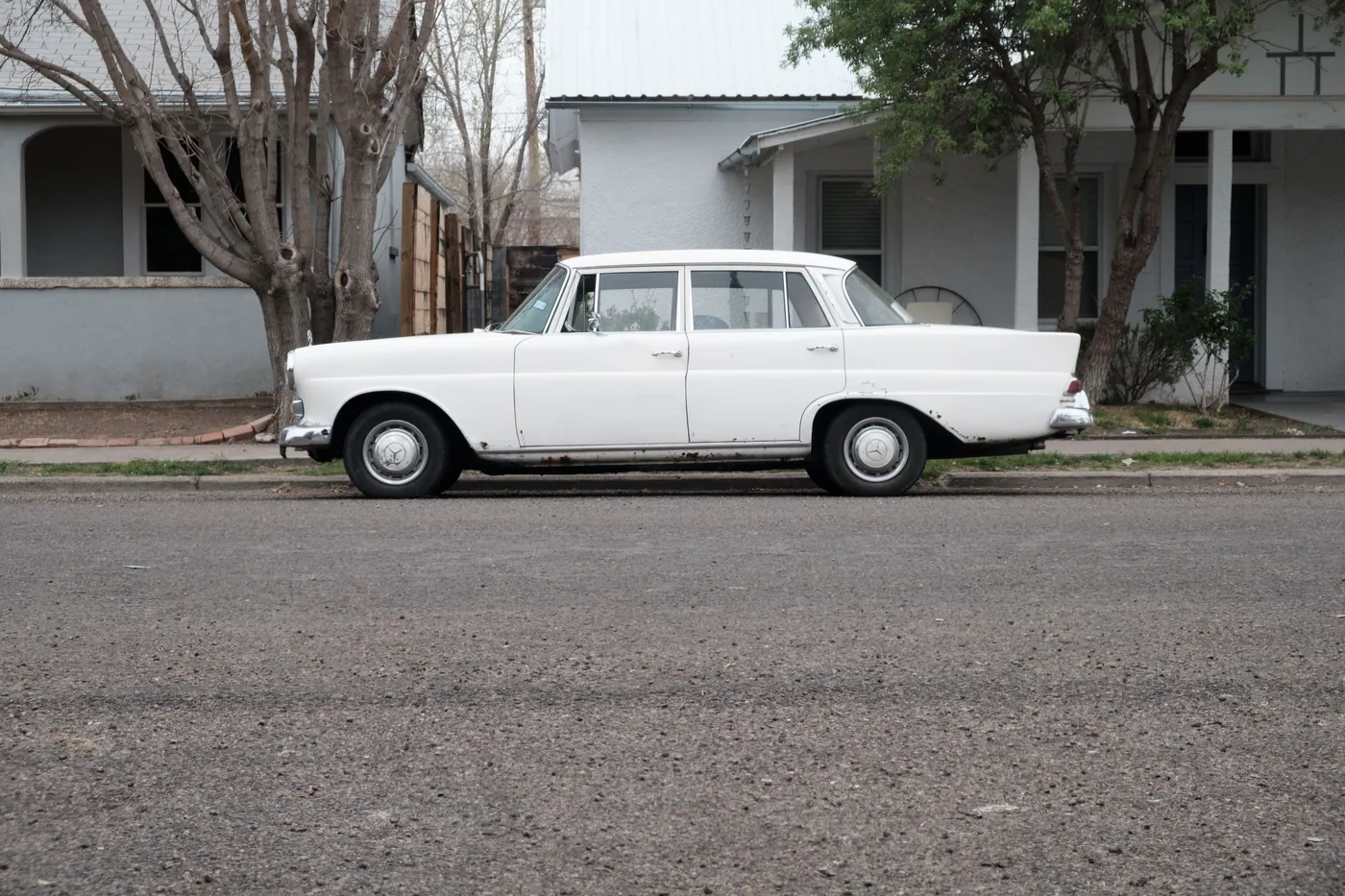 A white sedan parked on a quiet residential street.